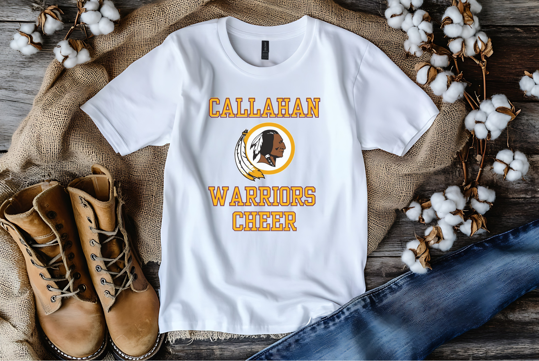 White t-shirt with 'Callahan Warriors Cheer' design on a rustic wooden surface with boots and cotton.