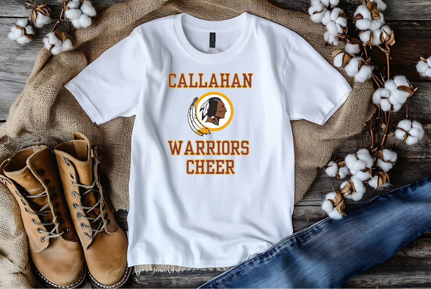 White t-shirt with 'Callahan Warriors Cheer' design on a rustic wooden surface with boots and cotton.